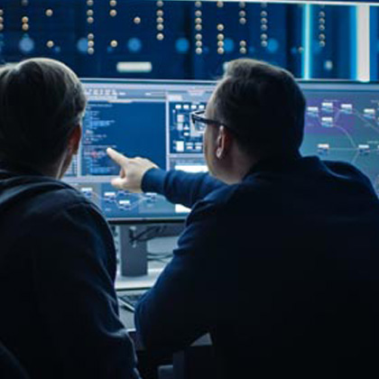 Two individuals analyzing data on computer screens in a tech environment.