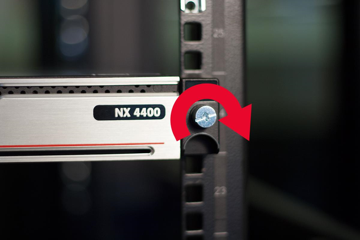Close-up of a rack-mounted appliance front panel labeled NX 4400 showing a screw and a large red curved arrow indicating to turn the screw clockwise