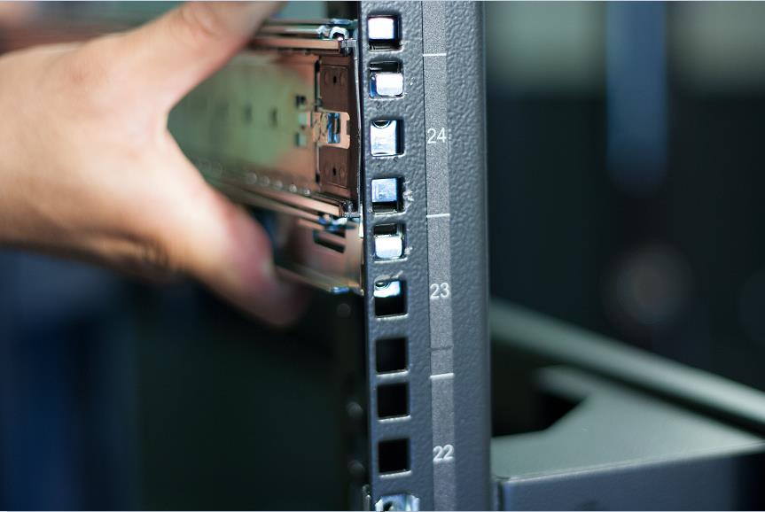 Close-up of a hand installing a server rail into a rack, showing rack unit markings 24, 23, 22 and the edge of the rack column