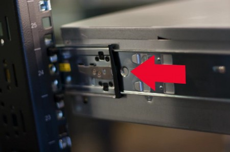 Appliance partially inserted into rack inner rails with a large red arrow indicating direction to push the appliance fully into the rack