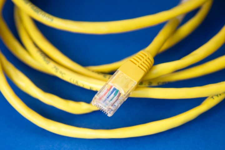 A yellow Ethernet cable coiled on a blue background, showcasing its connector and wiring.